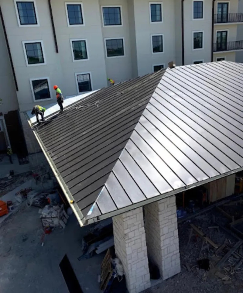 Crew installing standing seam metal roof panels on a commercial project in Prior Lake